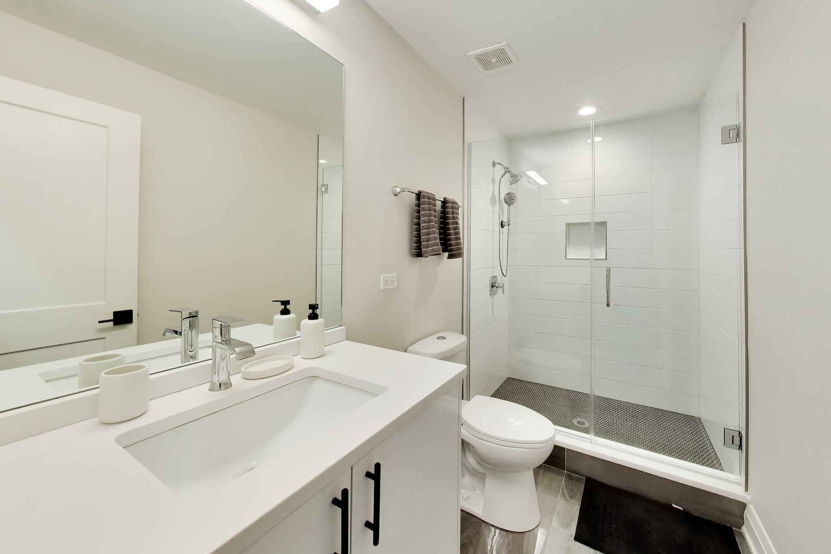 Modern bathroom with a white vanity and glass-enclosed tiled shower.