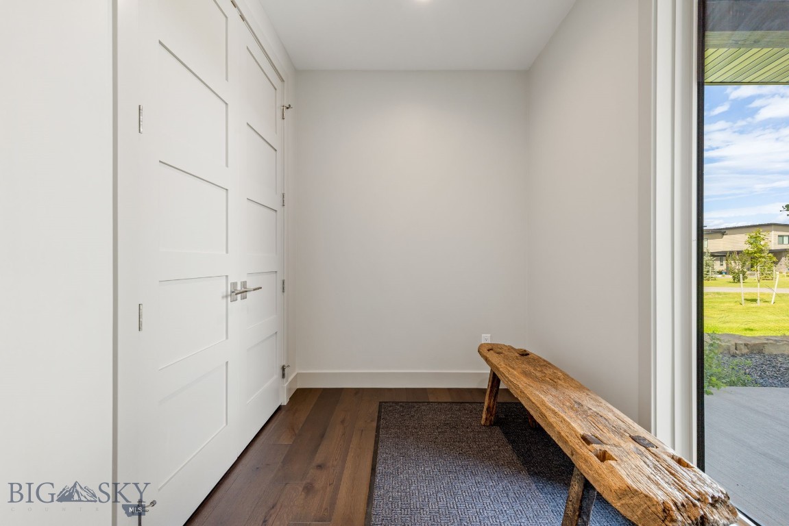 Entryway with a rustic live-edge bench, woven rug, and large window overlooking a green lawn.