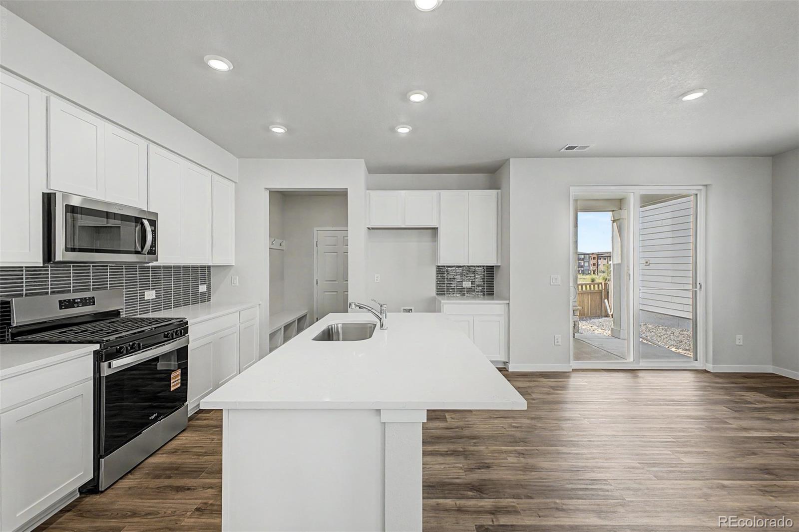 Kitchen with white cabinets, a large island, stainless appliances, and sliding doors to a patio.