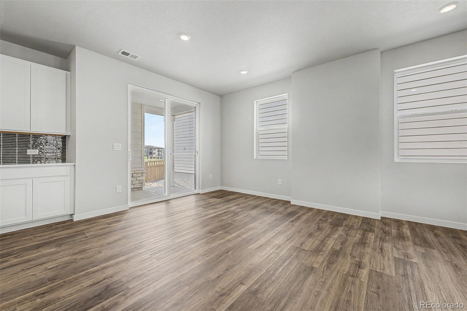 Empty room with wood-look flooring, white cabinetry, and sliding glass doors to a patio.