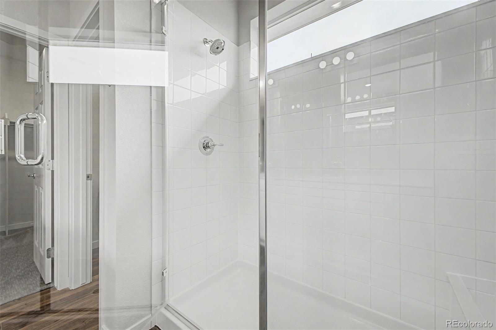 White-tiled shower with a clear glass enclosure and chrome fixtures.