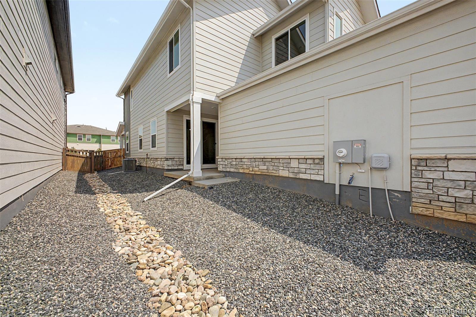 House side yard with gravel landscaping, a stone path, and exterior utility meters.