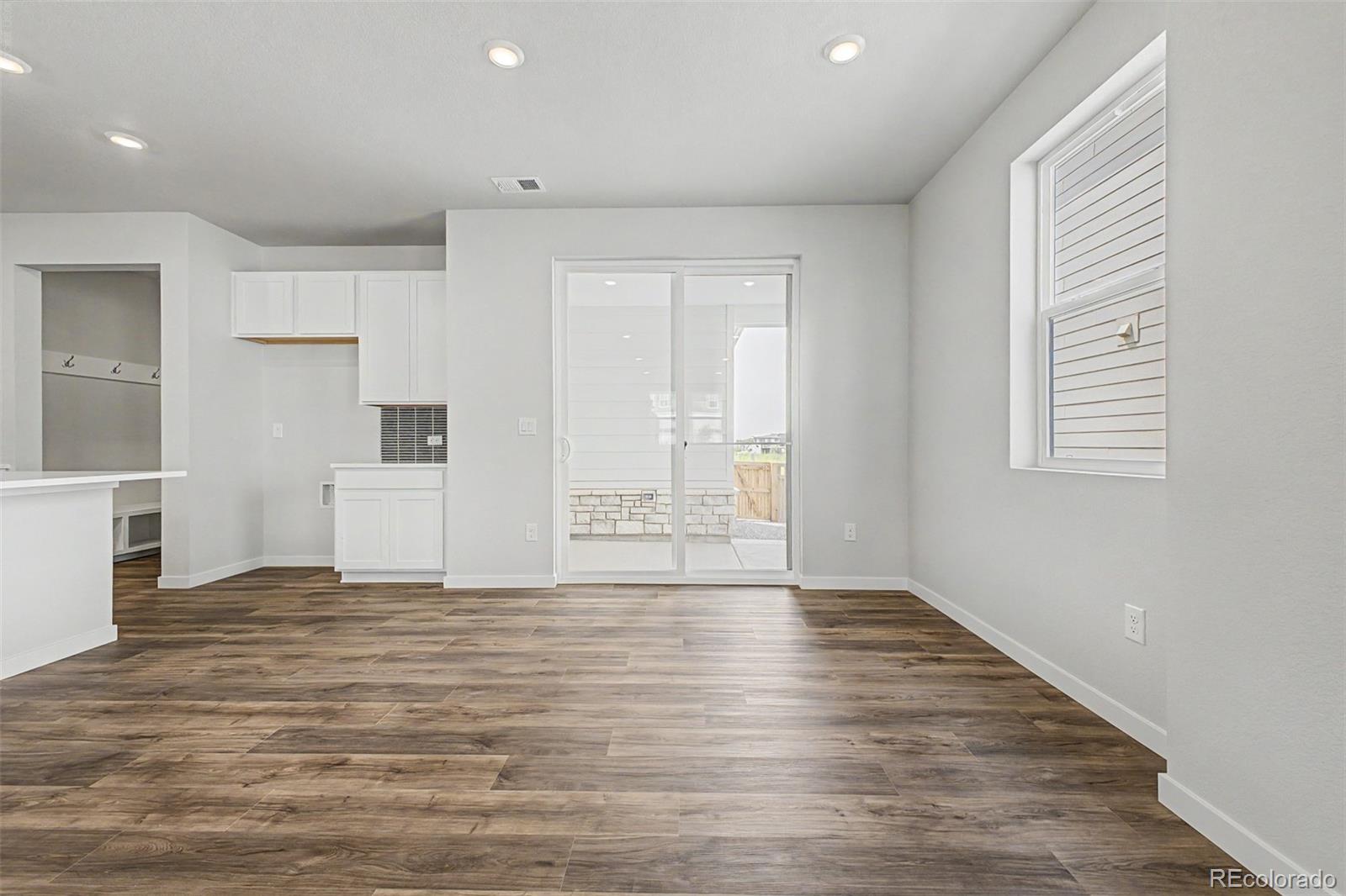 Bright empty room with wood-look floors, built-in cabinets, and sliding glass doors to a patio.