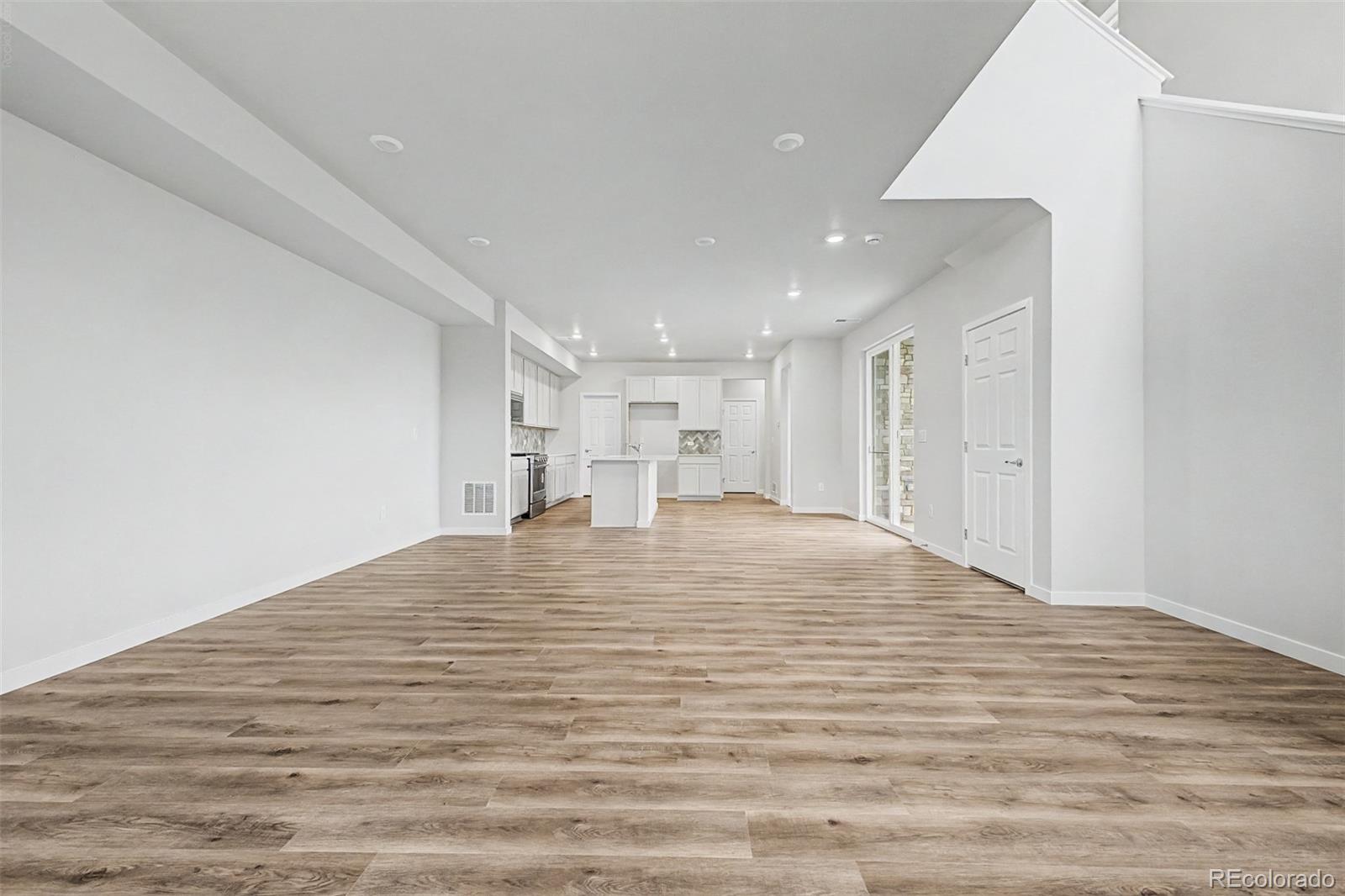 Vacant open-plan living room with wood-look floors and a kitchen island.