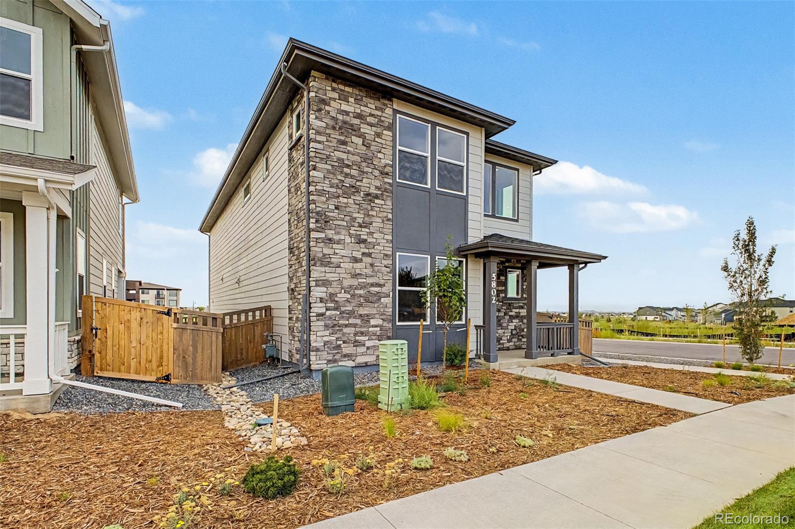 Two-story home with a stone facade, covered porch, and landscaped front yard.