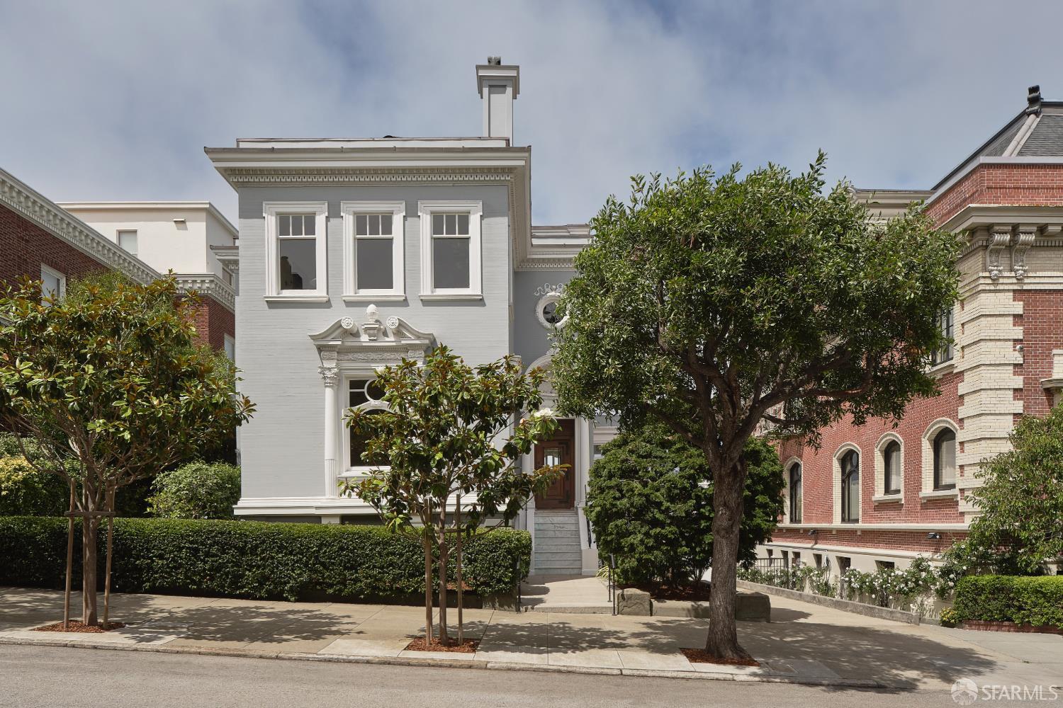 Gray San Francisco home with ornate white trim, a front stoop, and mature trees.