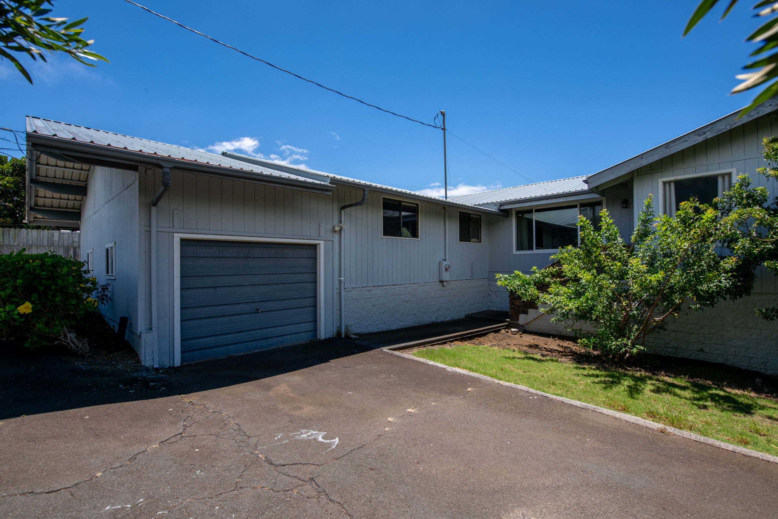 Single-story home with a metal roof, attached garage, and paved driveway.