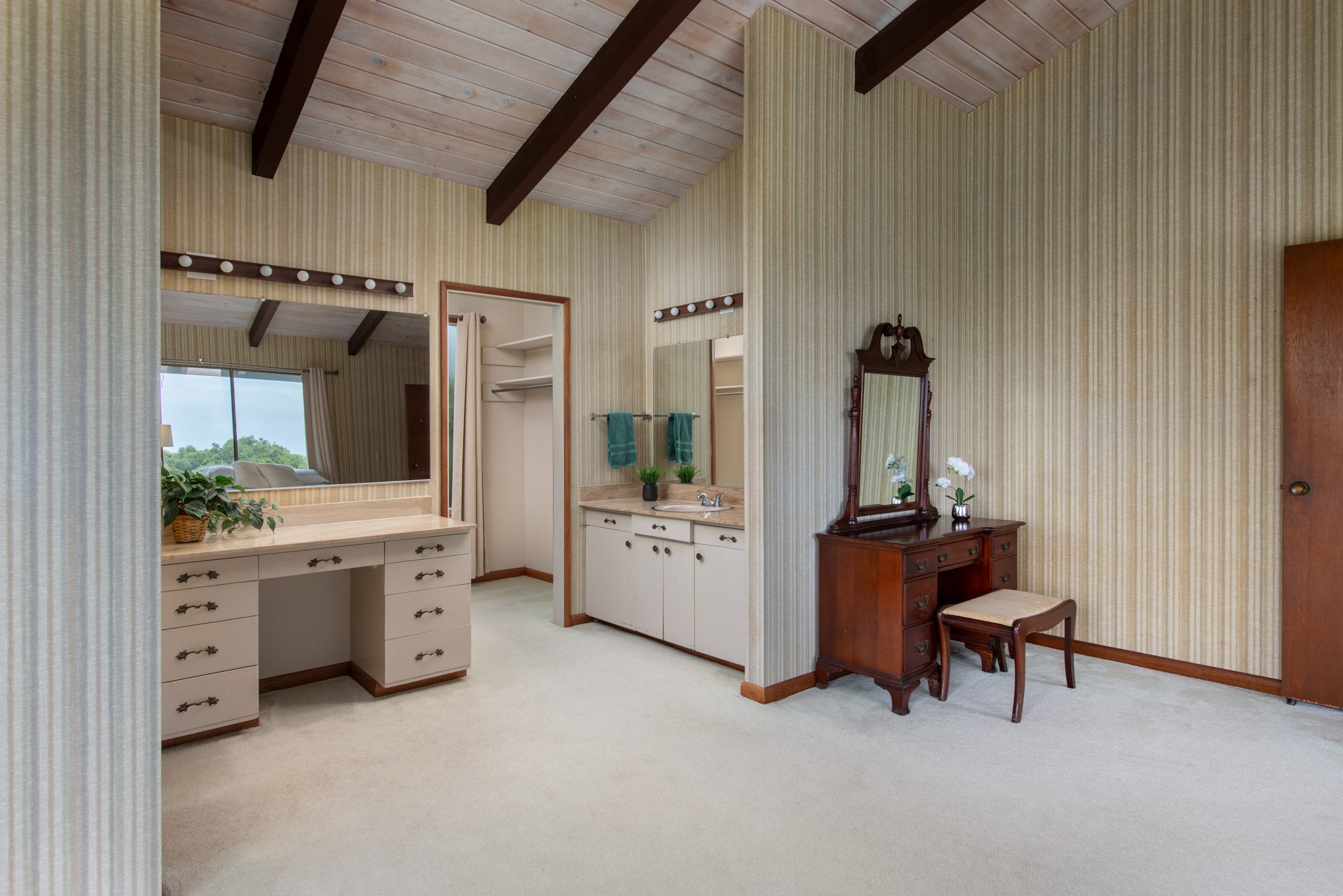 Dressing area with twin vanities, an open closet, and a vaulted wood-beam ceiling.