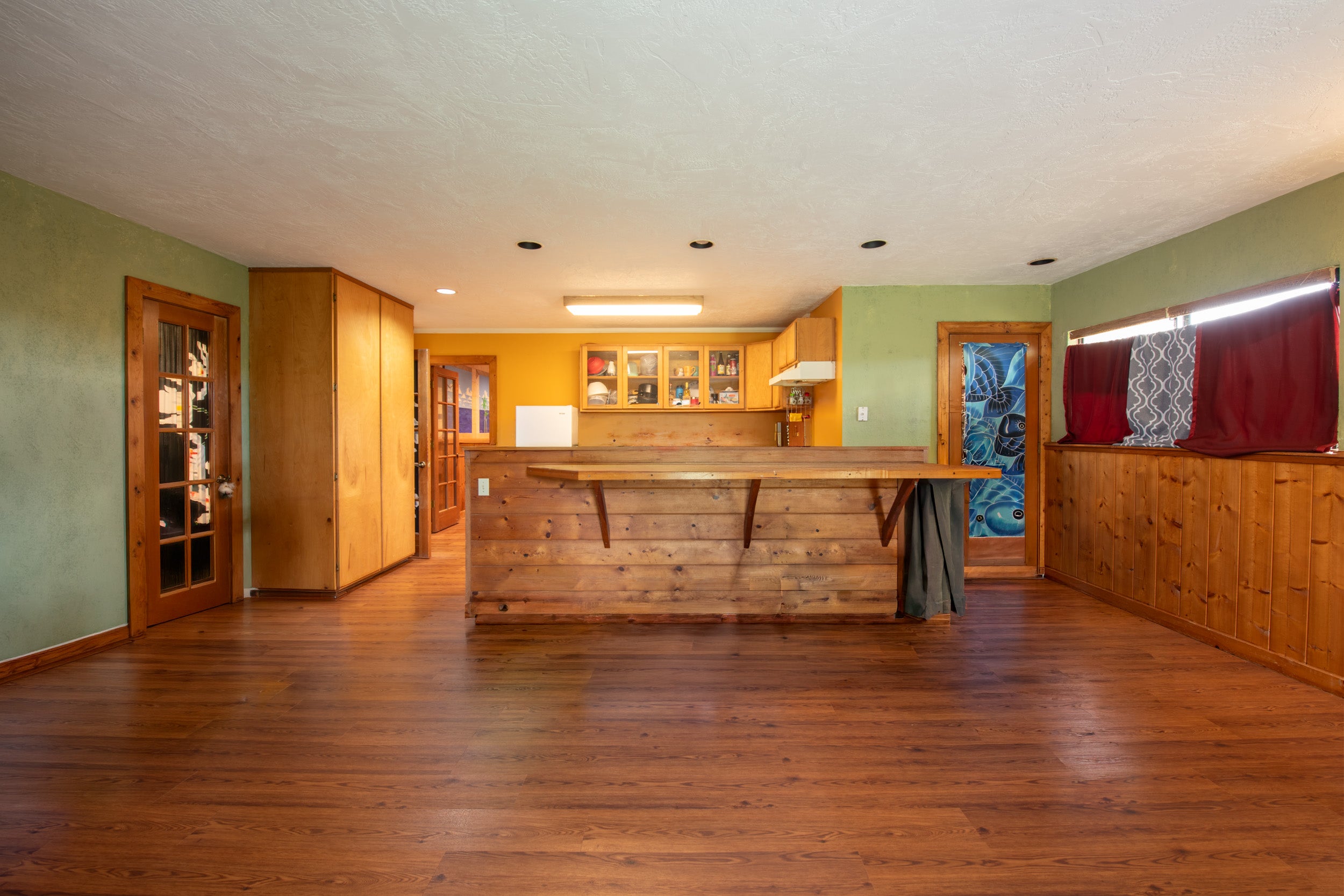 Interior with a long rustic wood counter, hardwood floors, and yellow kitchen cabinetry.
