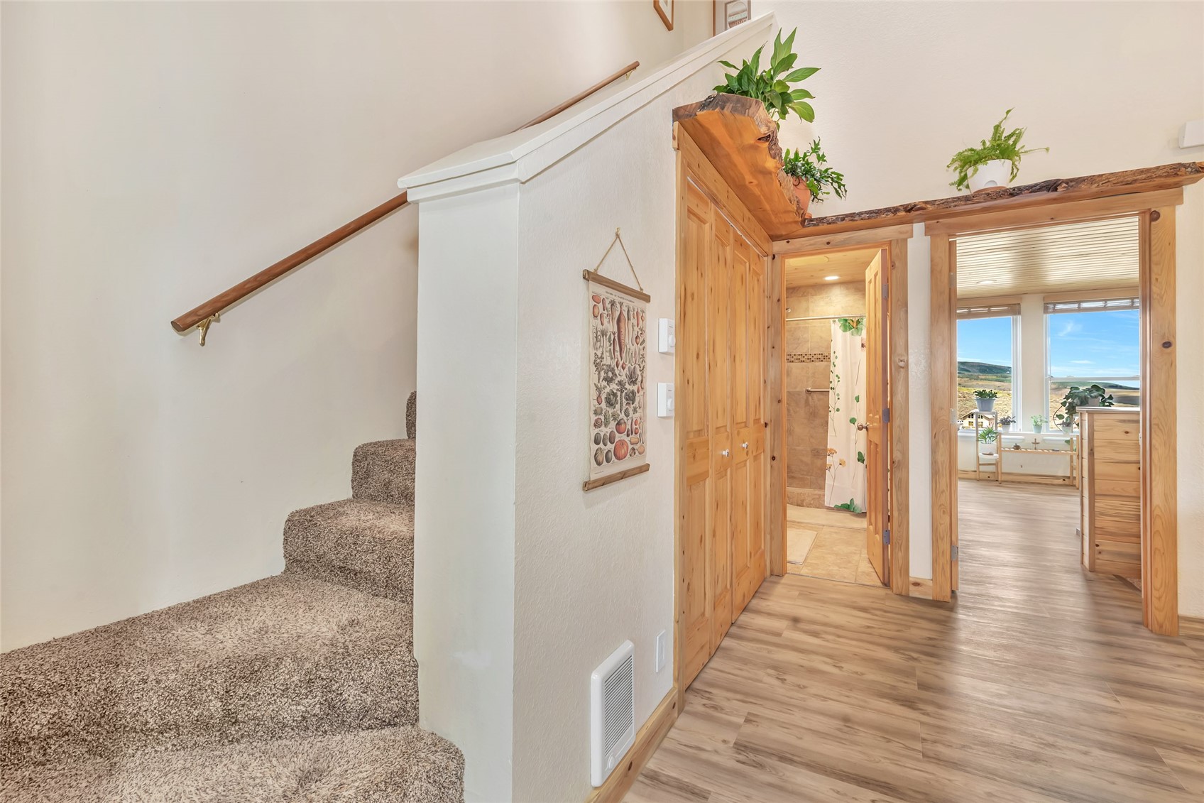 Hallway with carpeted stairs, wood-trimmed doorways, and windows overlooking rolling hills.