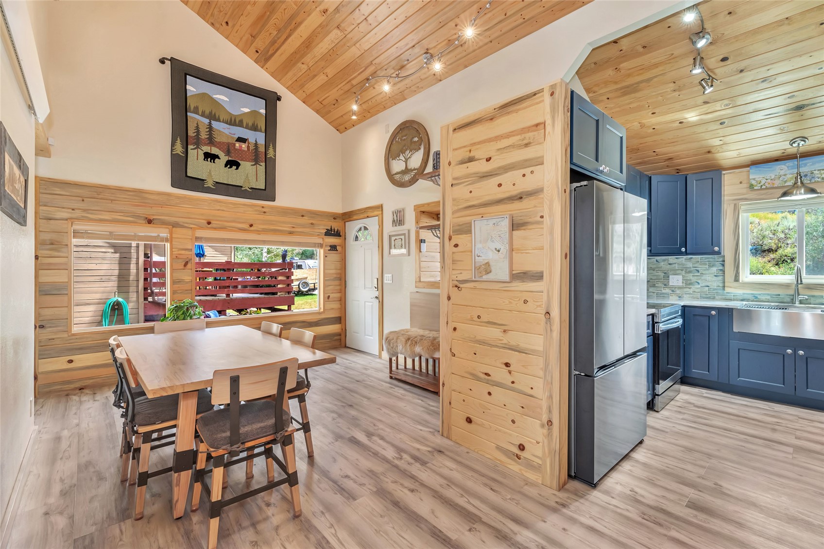 Open-plan kitchen and dining area with blue cabinets, a vaulted wood ceiling, and a large dining table.