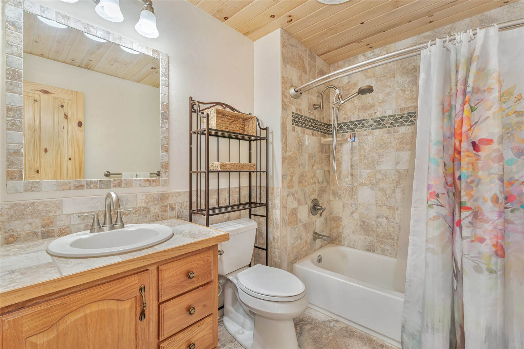 Bathroom with a wood vanity, tiled tub and shower, and wood-plank ceiling.