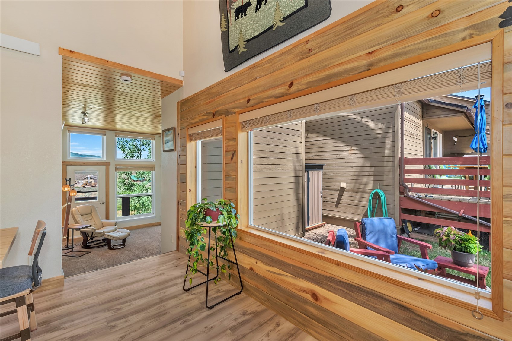 Living area with a large wood-trimmed window overlooking a courtyard and a recliner beside tall windows.