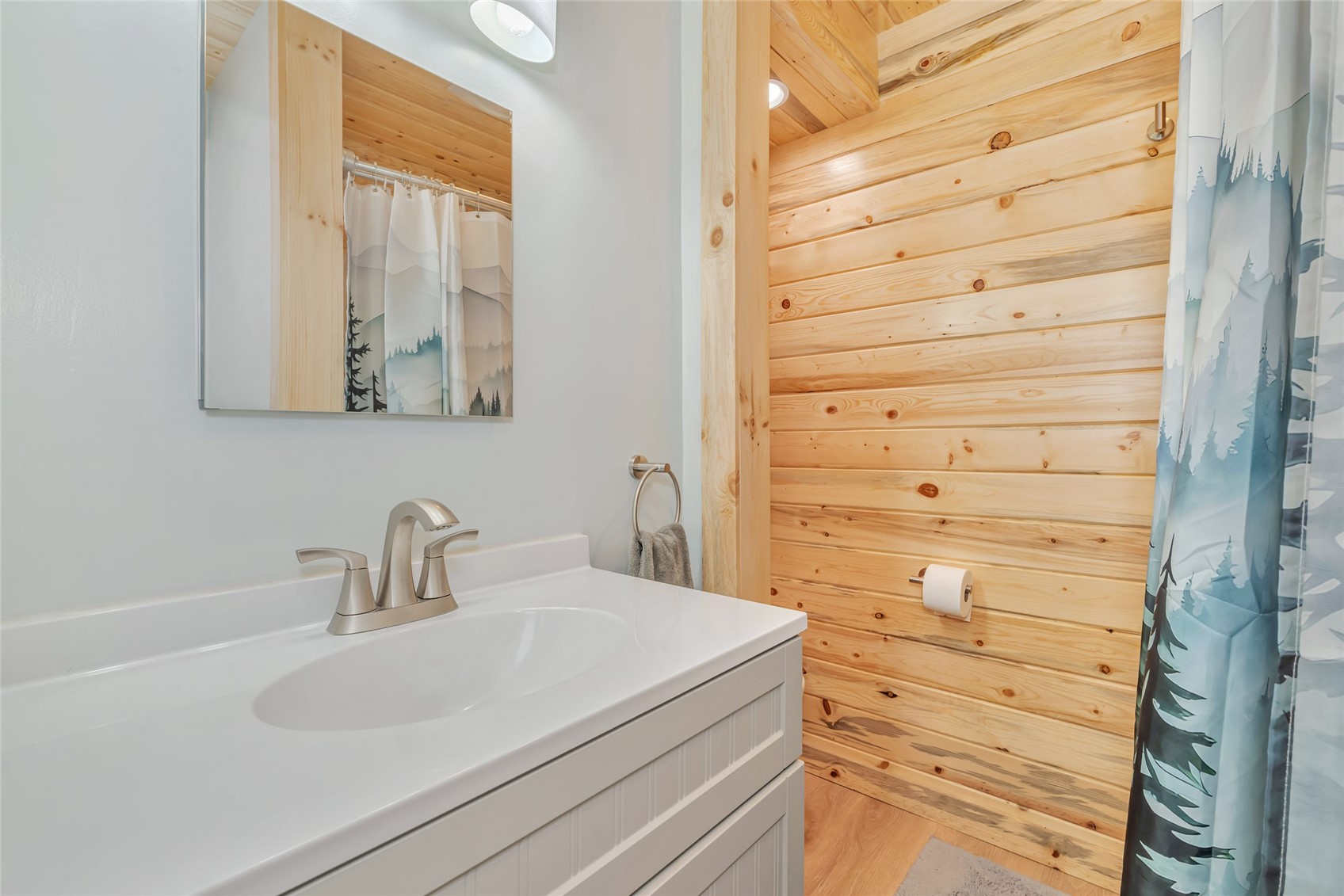 Bathroom with a white vanity and a natural wood-plank shower surround.
