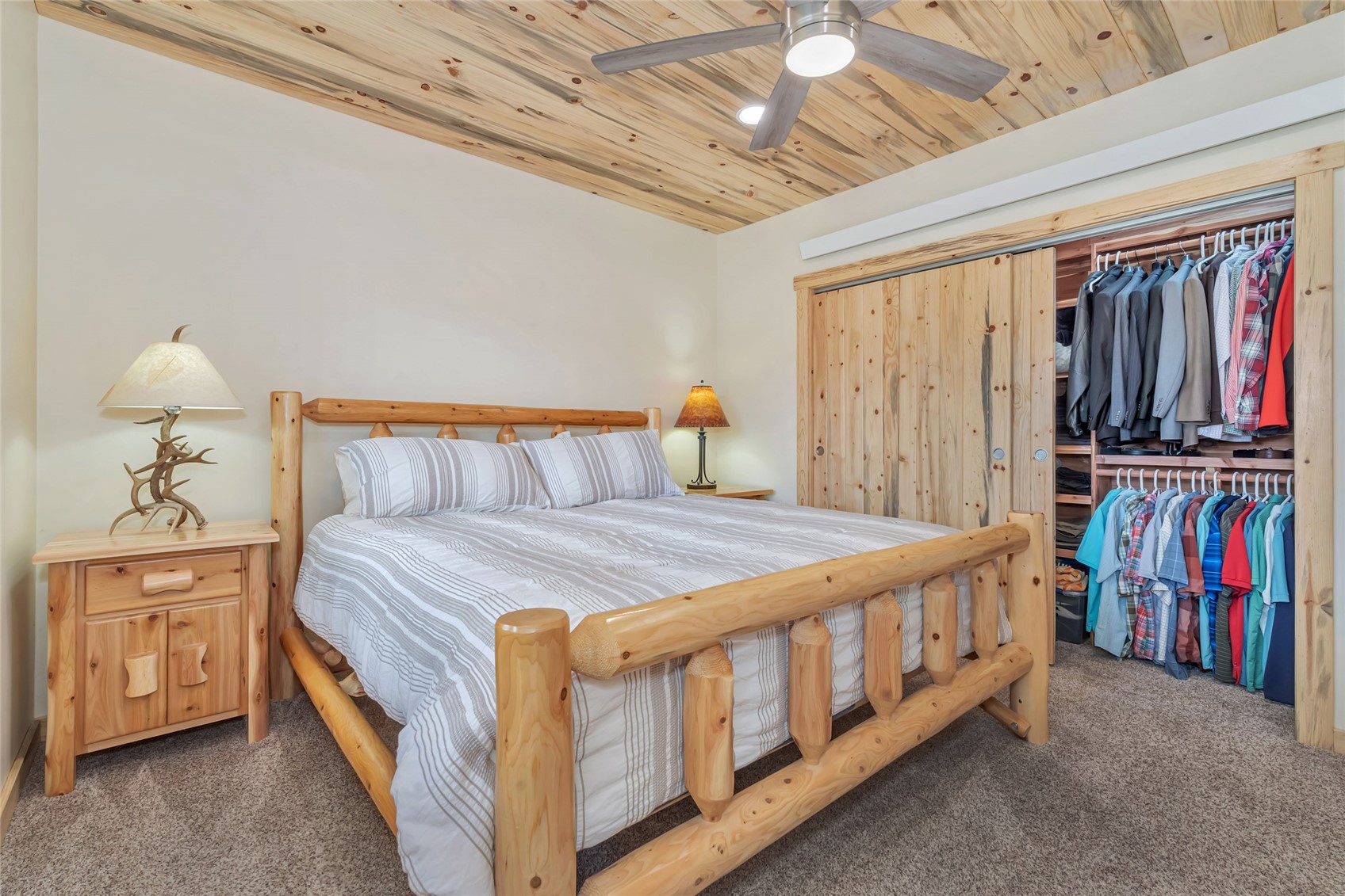 Bedroom with a log bed, knotty-pine ceiling, and open clothes closet.