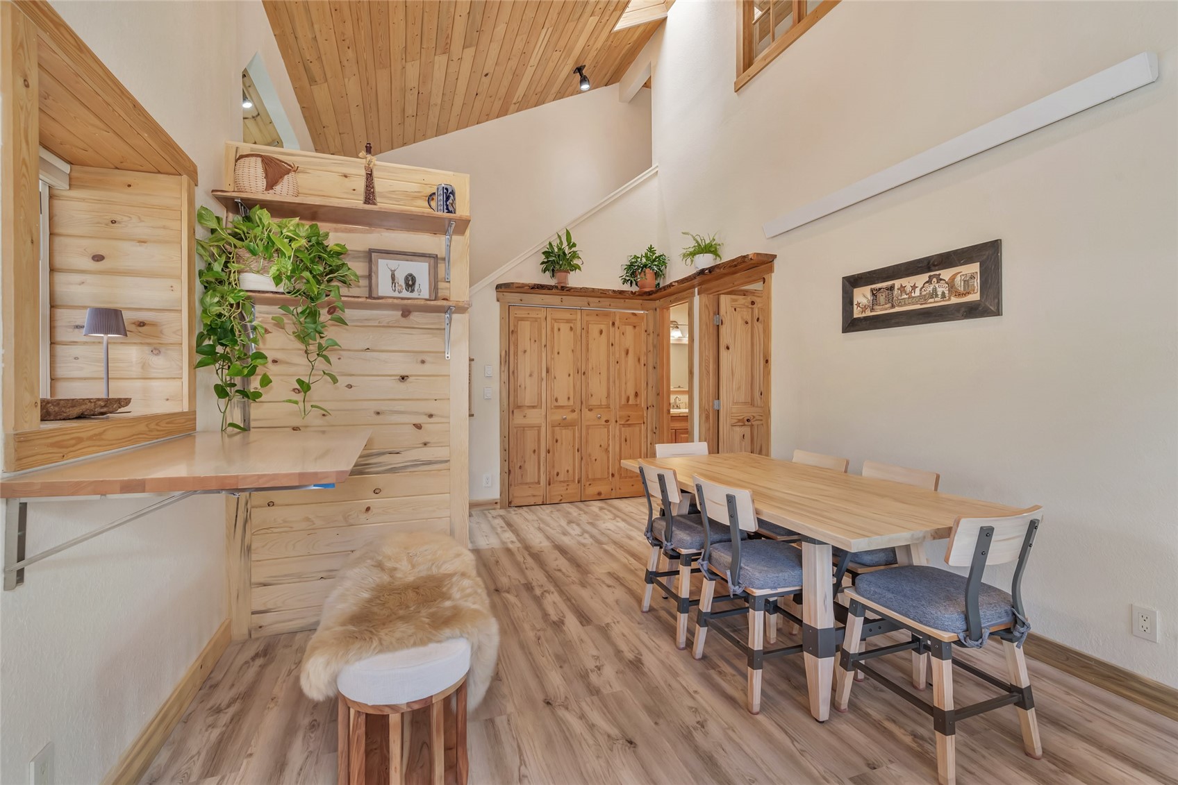 Dining area with a light-wood table, pine cabinetry, built-in shelving, and a high wood-plank ceiling.