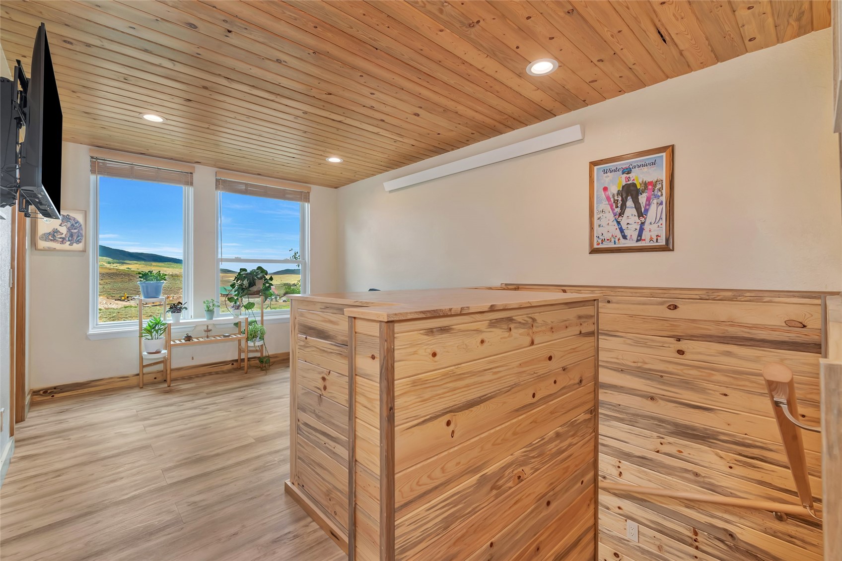 Interior room with a wood-plank ceiling, matching counter, and windows overlooking rolling hills.