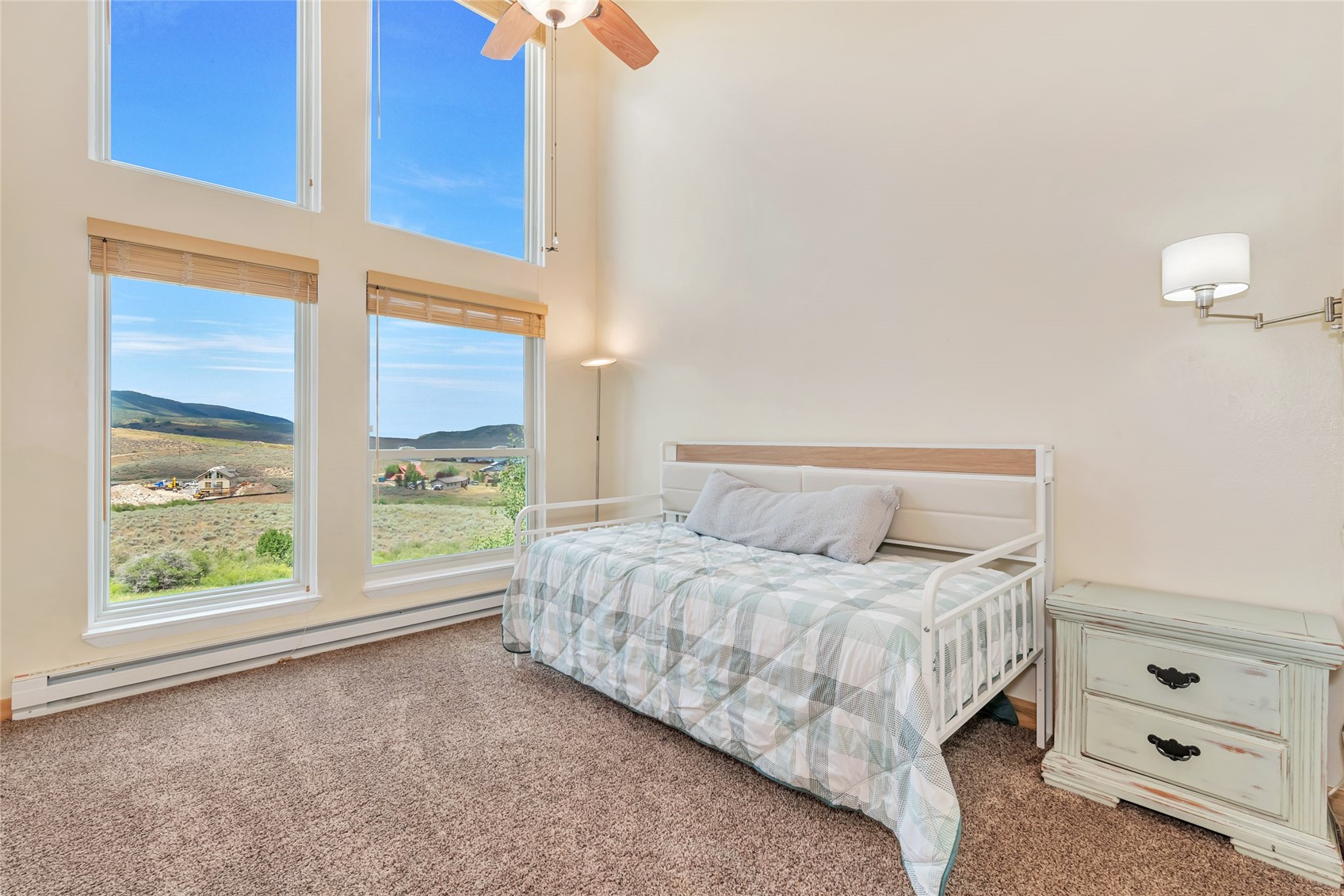 Bedroom with a white daybed and tall windows overlooking rolling hills.