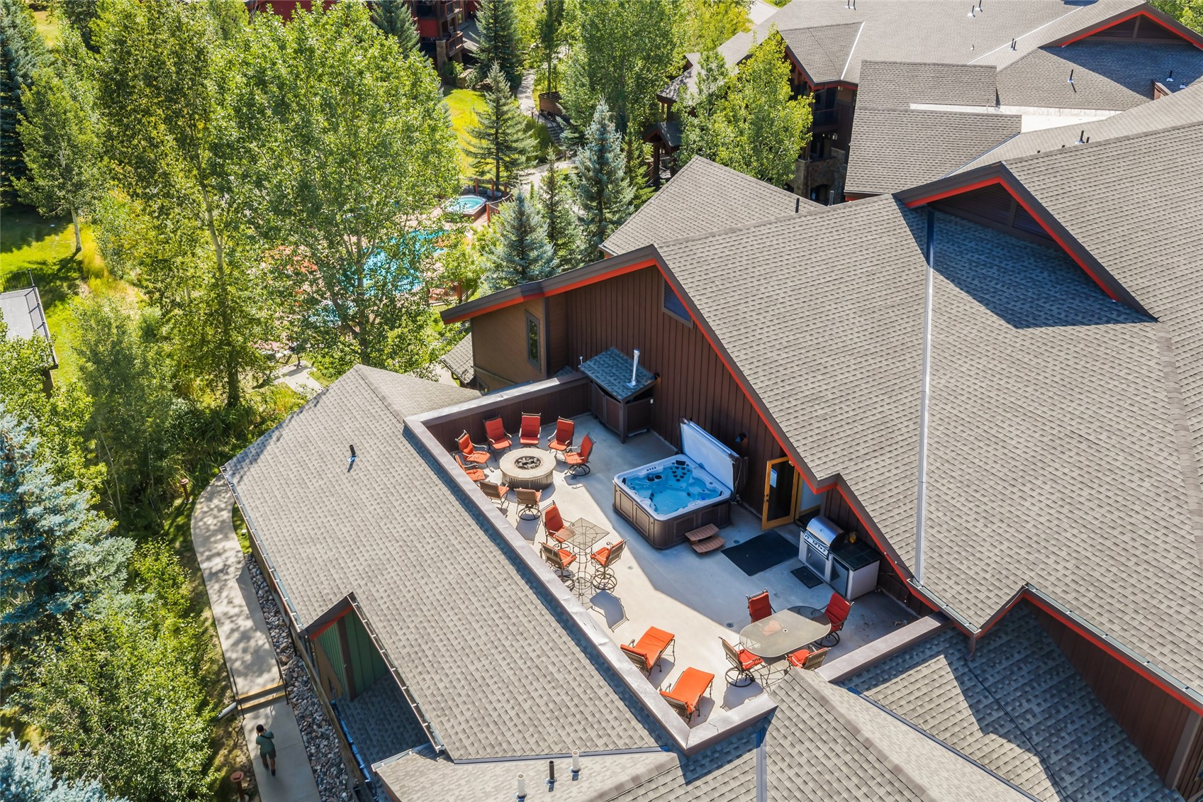 Aerial view of a residence with a rooftop terrace, hot tub, orange chairs, and fire pit.
