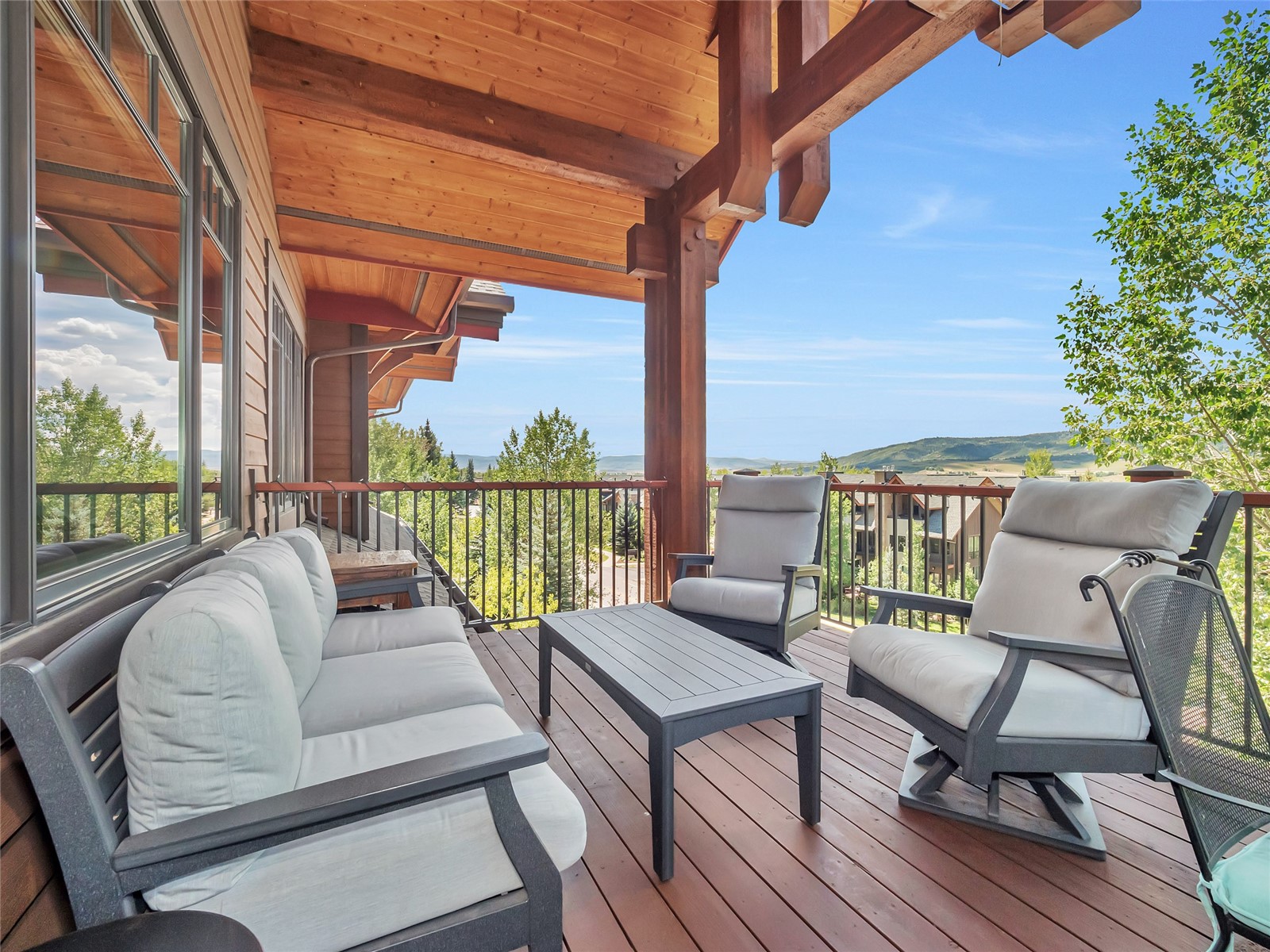 Covered deck with cushioned seating and mountain views beyond the railing.