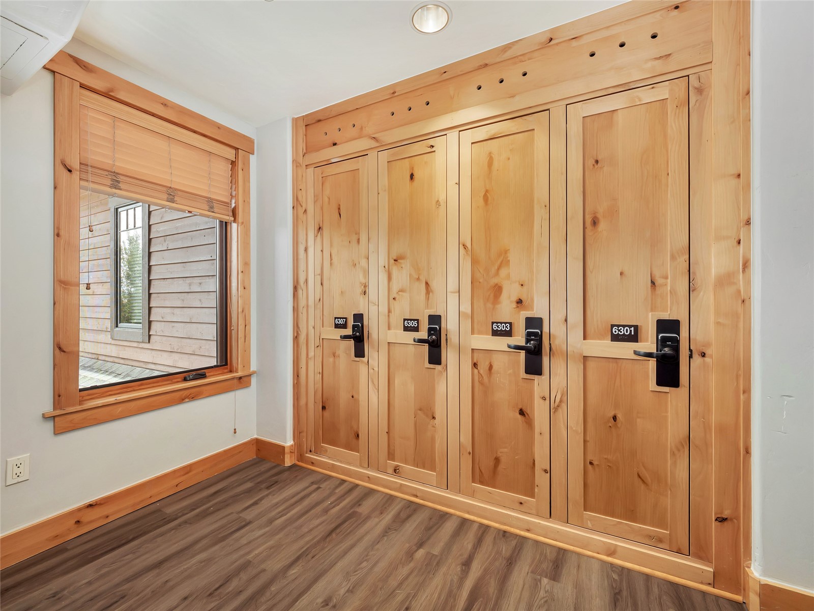 Hallway with four numbered wood doors and a window with blinds.
