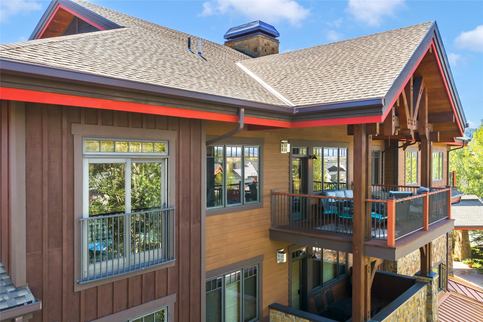 Mountain-style building with timber framing, stone accents, and covered balconies with outdoor seating.
