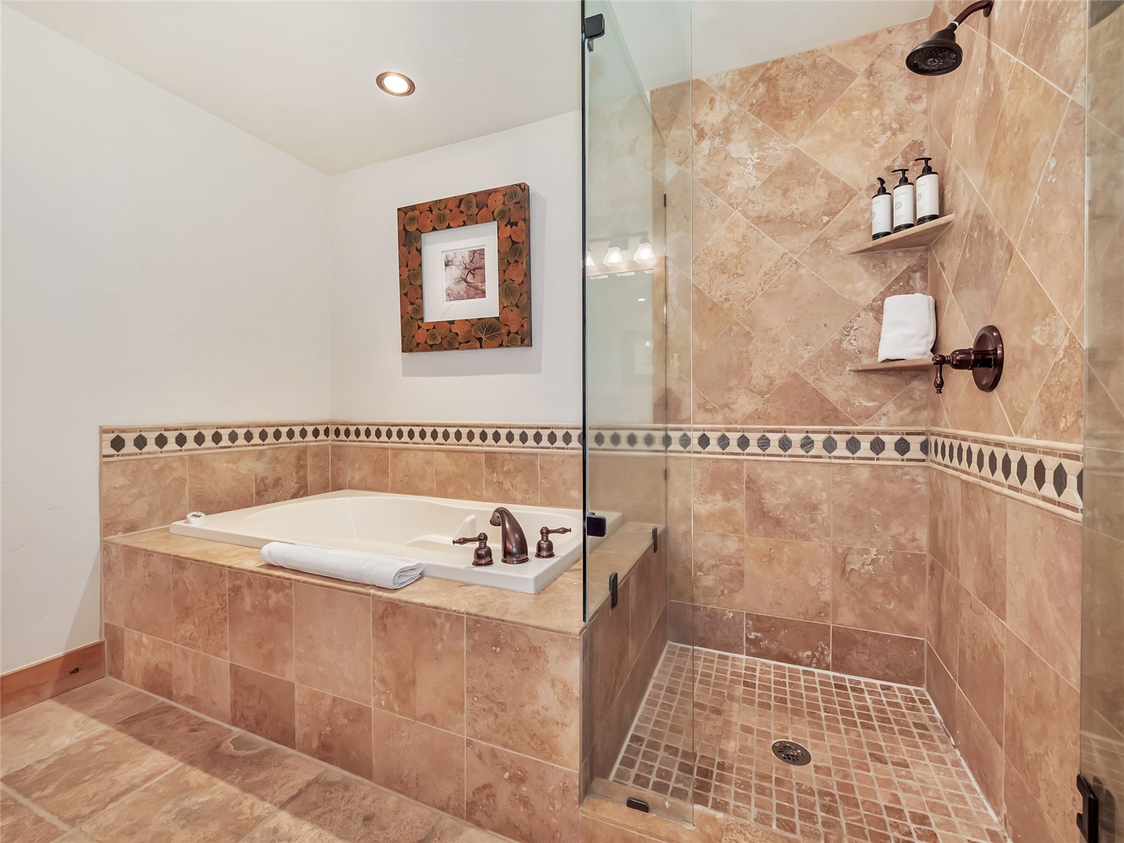 Tiled bathroom with a built-in soaking tub and glass-enclosed walk-in shower.
