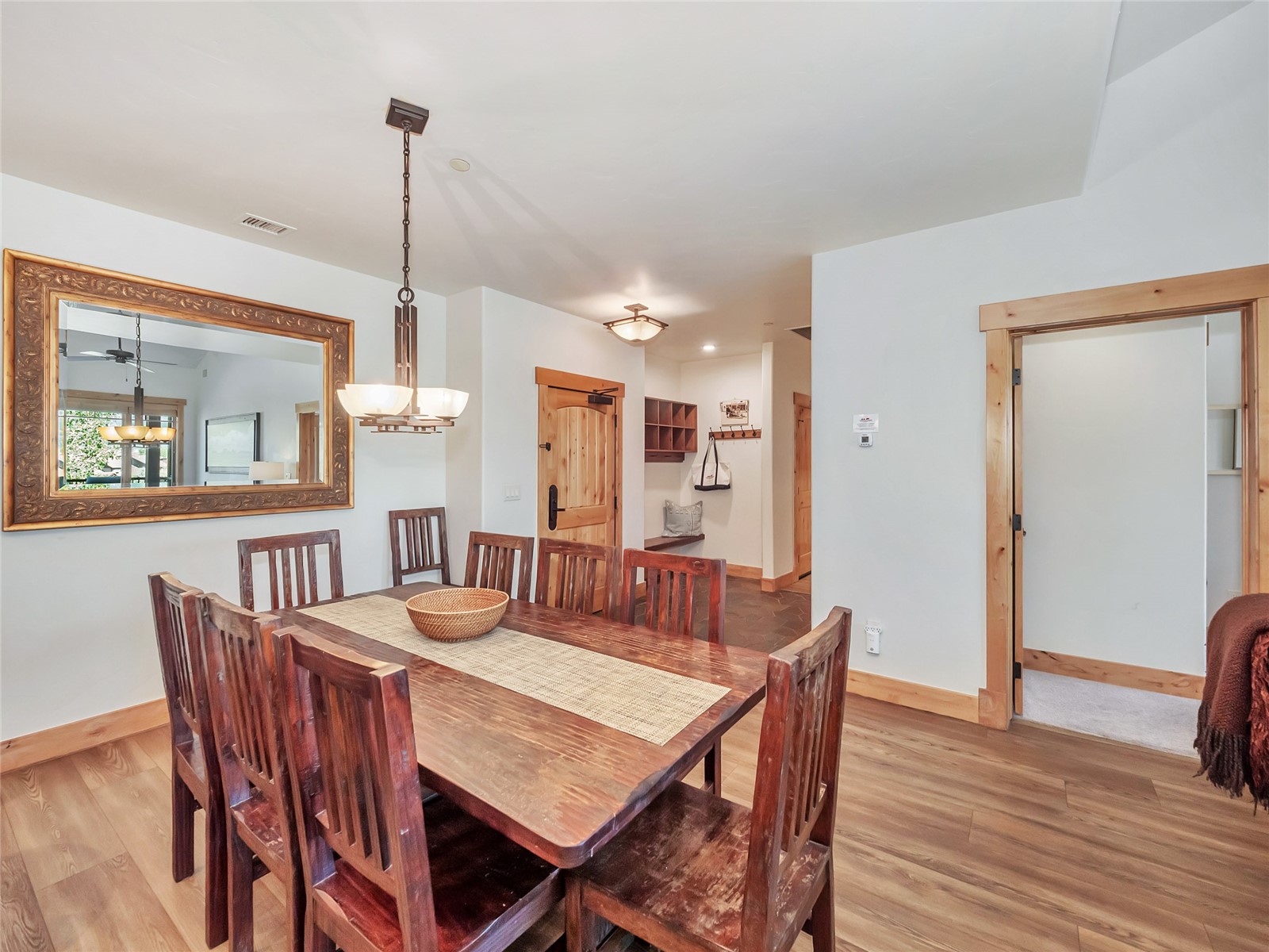 Dining room with a rustic wooden table, matching chairs, and a large ornate mirror.
