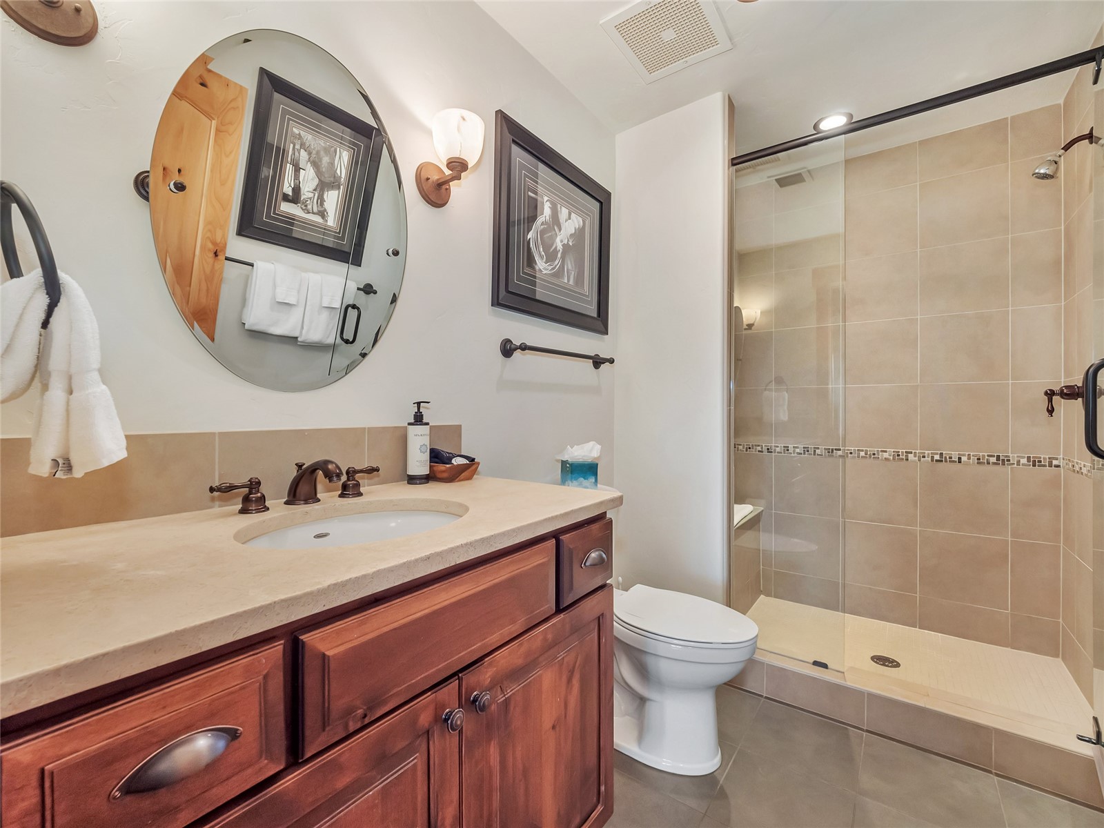 Bathroom with a dark wood vanity and a glass-enclosed tiled shower with mosaic accent band.