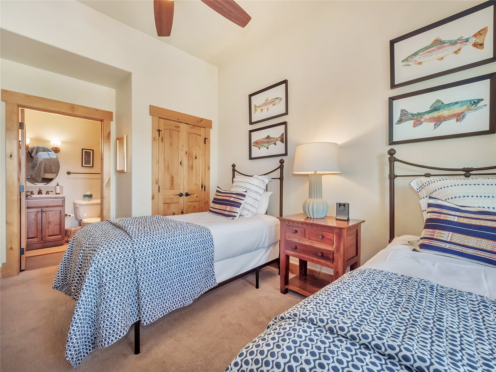 Bedroom with two twin beds, blue patterned bedding, and framed fish artwork.