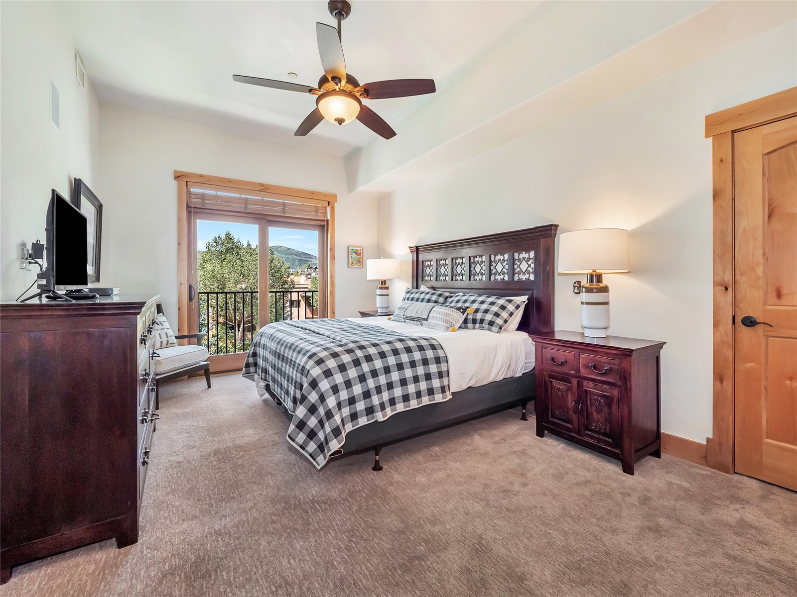 Bedroom with a checkered bedspread and balcony door overlooking a mountain.