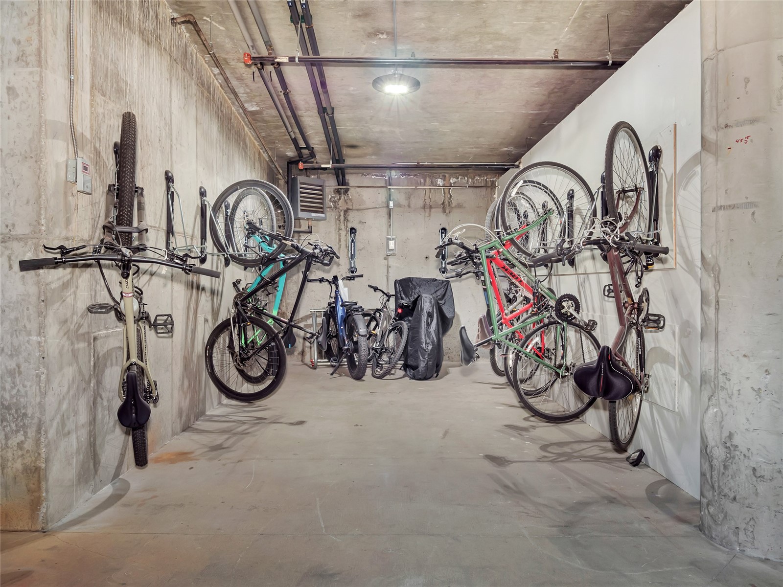 Concrete bicycle storage room with bikes mounted along both walls and parked in the center.