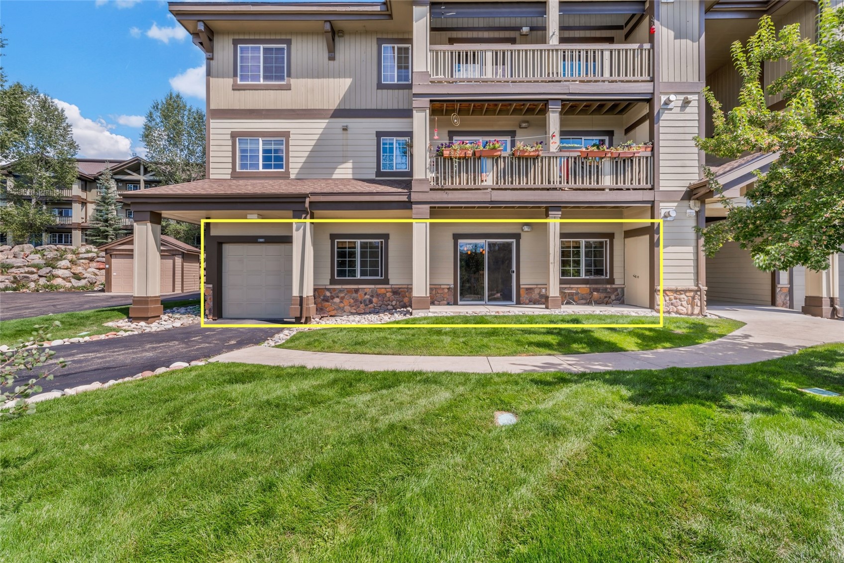 Ground-level condominium unit outlined in yellow, with a garage and sliding glass door.