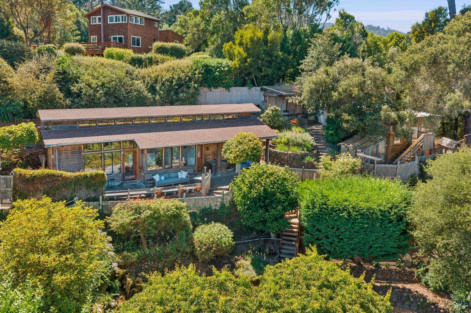 Wood-sided home on a lush hillside, with broad decks and terraced gardens.