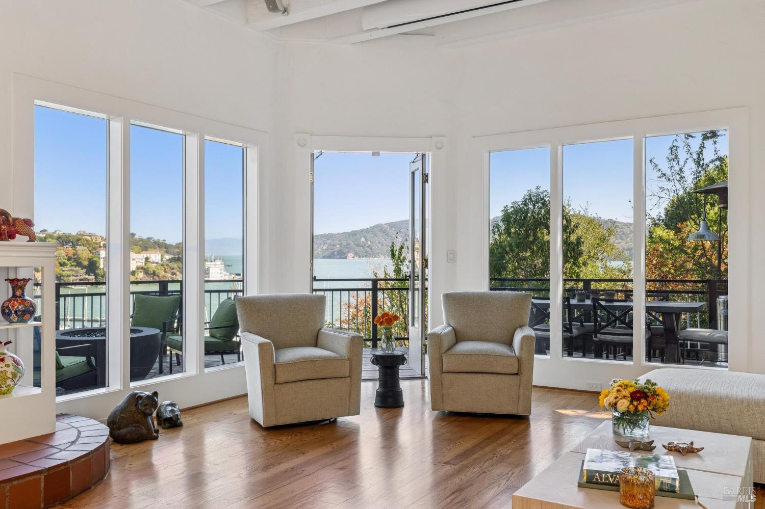 Bright living room with large windows overlooking the water and a furnished balcony.