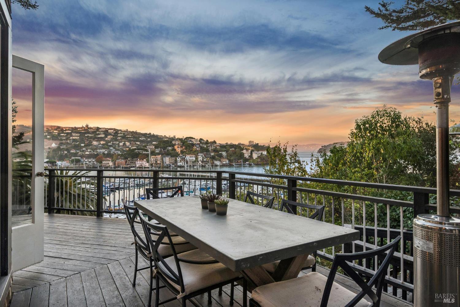 Furnished deck overlooking a marina and hillside homes at sunset
