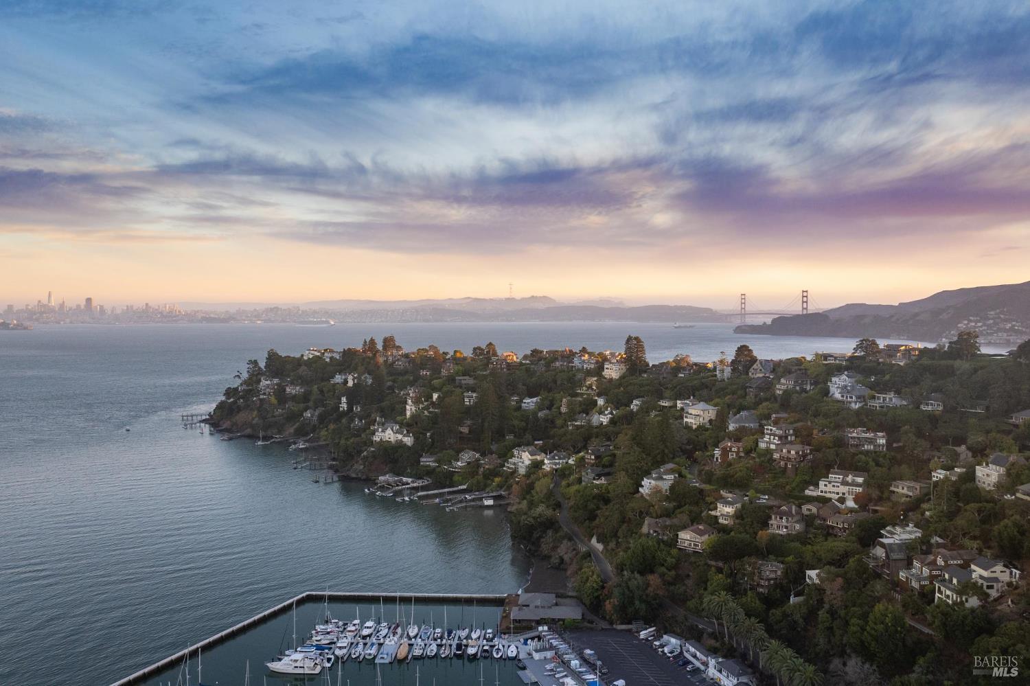 Aerial view of Belvedere homes, marina, San Francisco Bay, and Golden Gate Bridge at sunset.