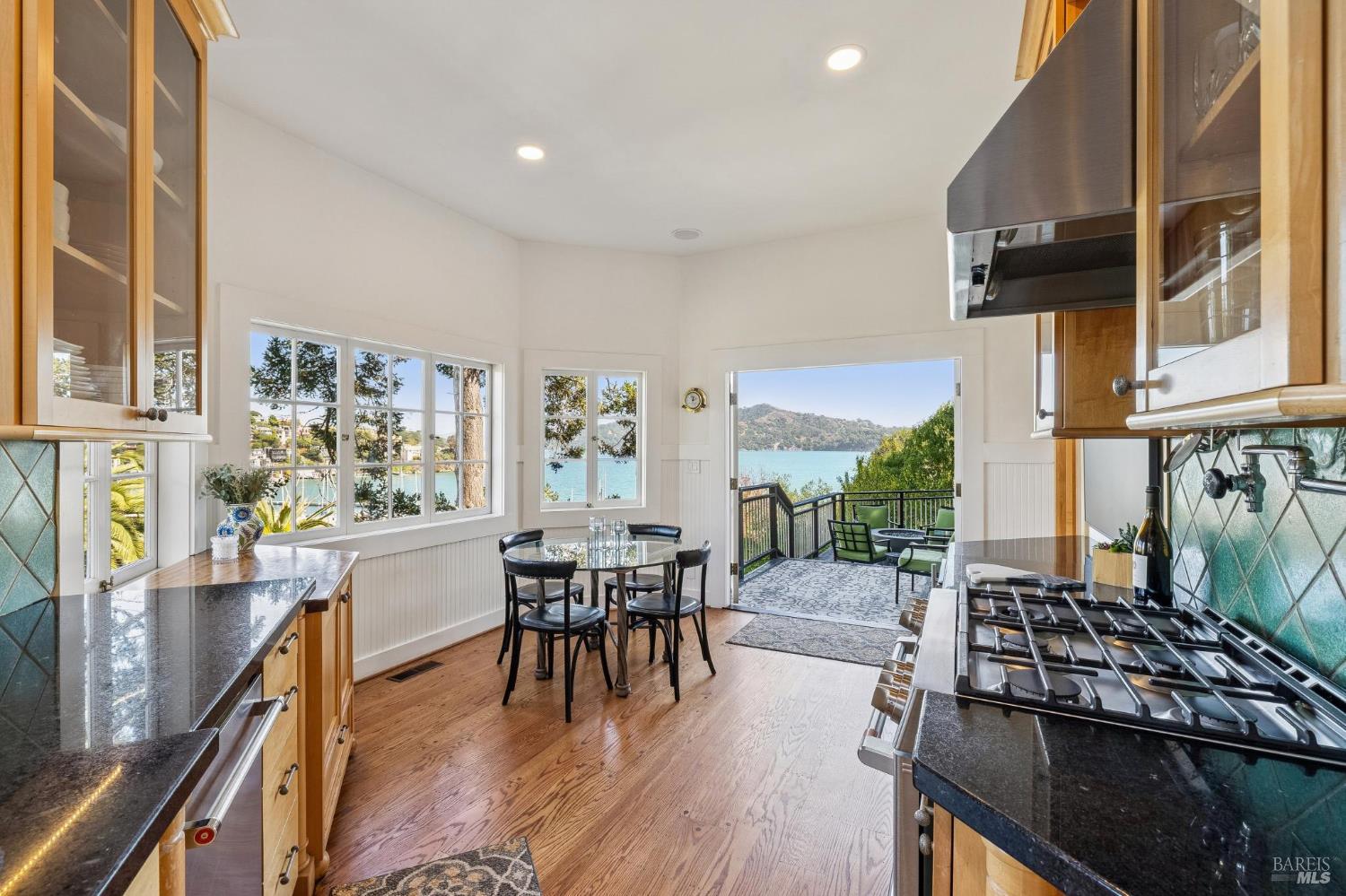 Kitchen with a dining table and broad windows overlooking the water and a deck.