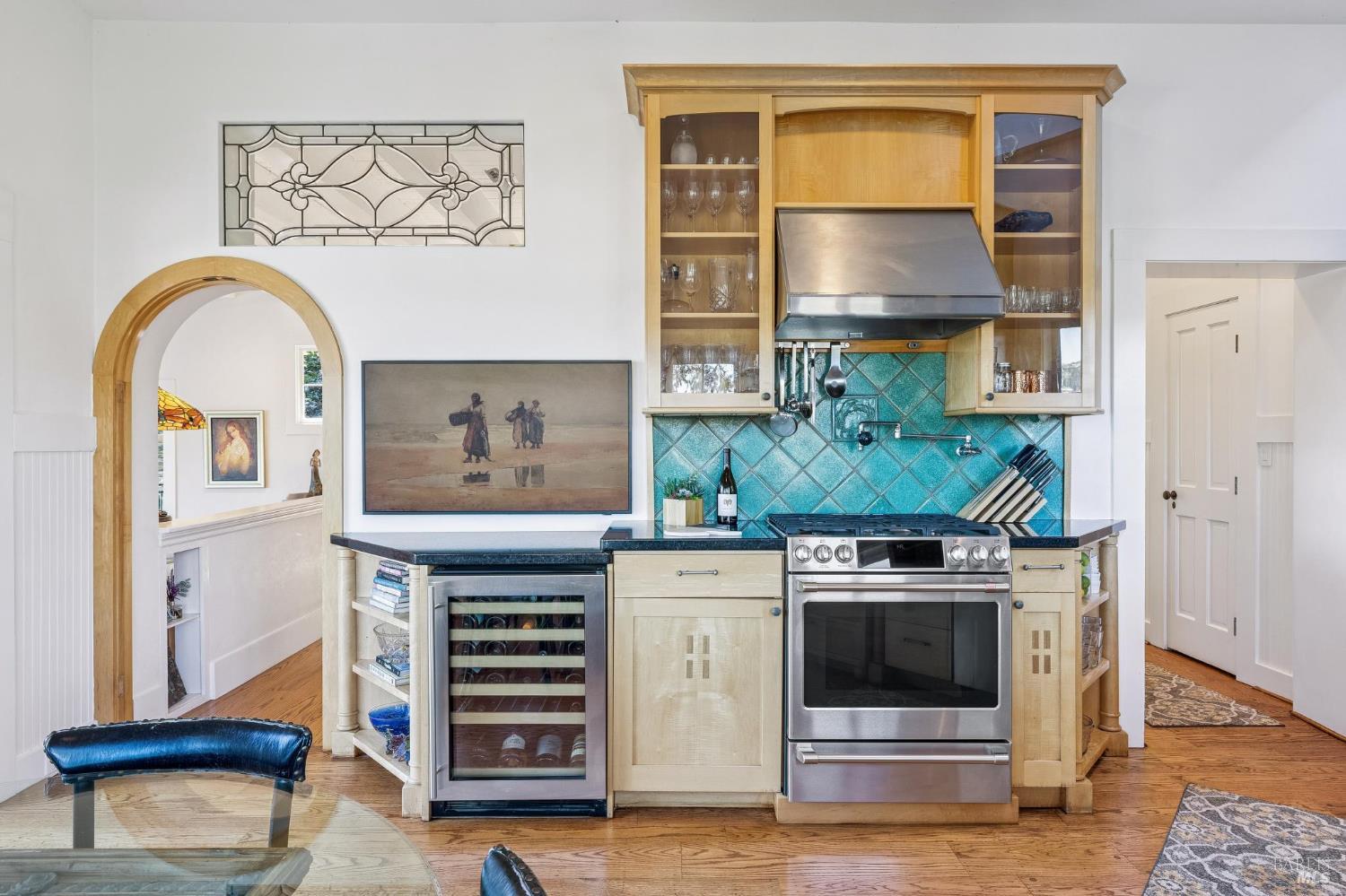 Kitchen with turquoise tile backsplash, stainless range, and custom wood cabinetry.