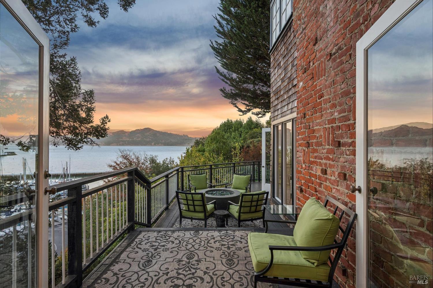 Furnished balcony with green seating overlooking a marina and bay at sunset.