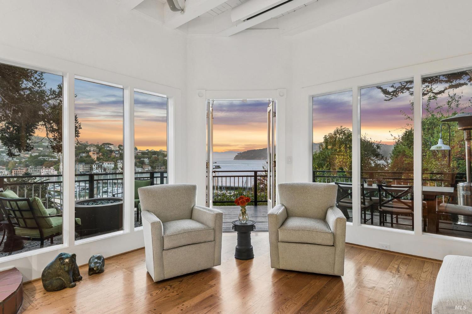 Living room with two armchairs and expansive bay views at sunset.