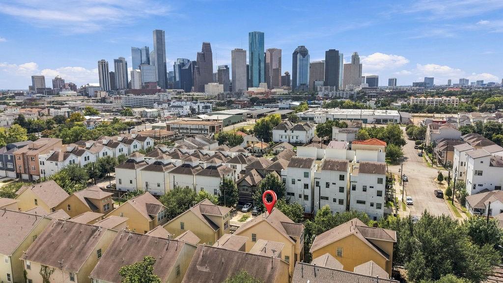Townhomes with downtown Houston’s skyline in the distance and a red location marker.