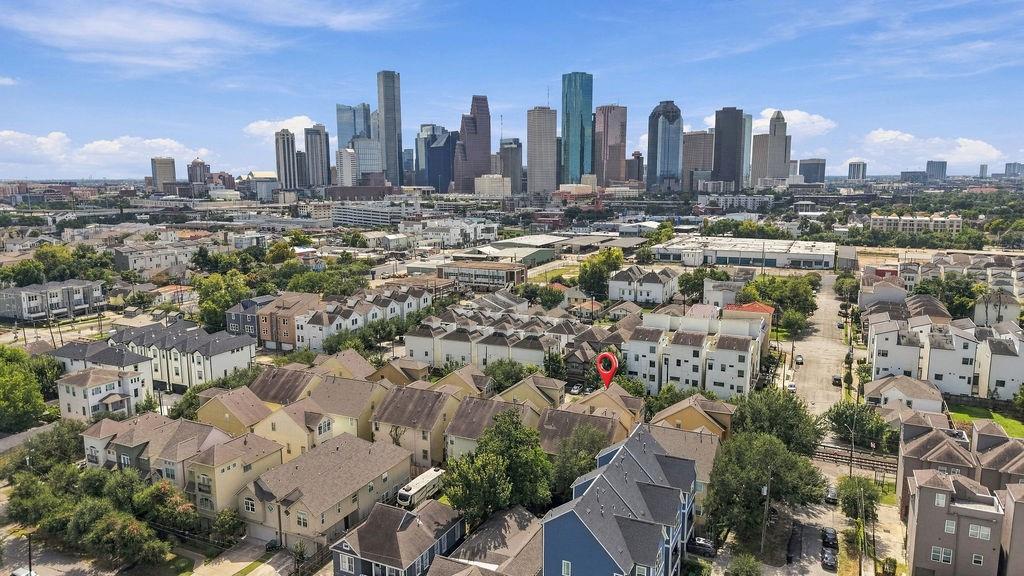 Aerial view of Houston townhomes and downtown skyline, with a red pin marking a home.