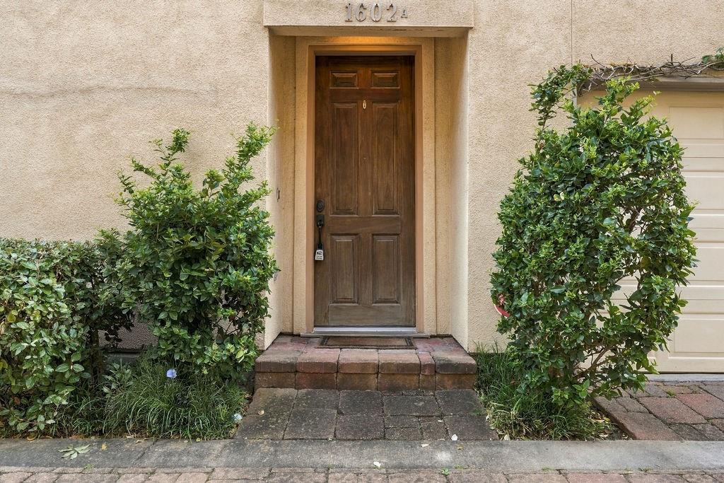 Home entrance with a dark wood door, brick steps, and trimmed shrubs.