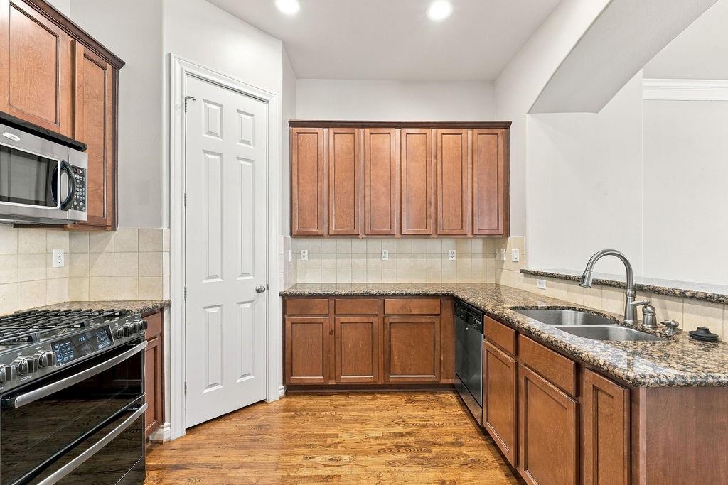 Kitchen with wood cabinets, granite counters, stainless appliances, and hardwood floors.