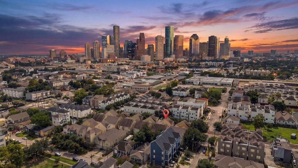 Aerial view of Houston homes with downtown skyline glowing beneath a colorful dusk sky.