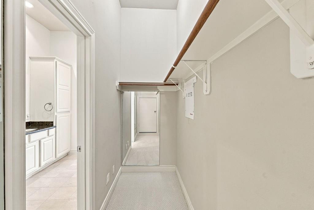 Walk-in closet with carpeted floor, hanging rods, and open shelving.