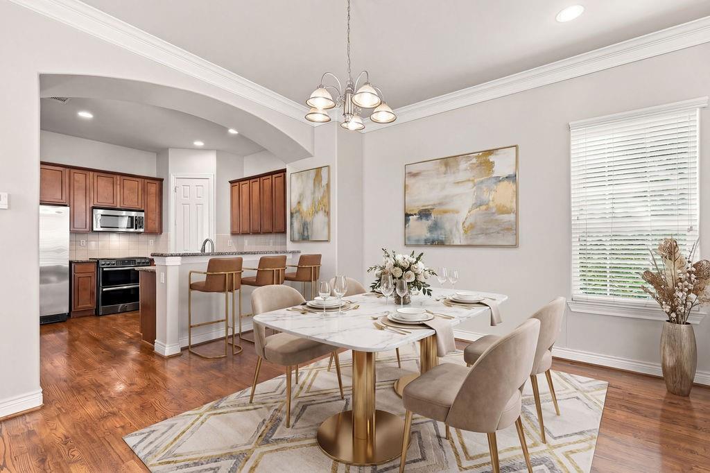 Dining room with a marble-top table and upholstered chairs beside an open kitchen.