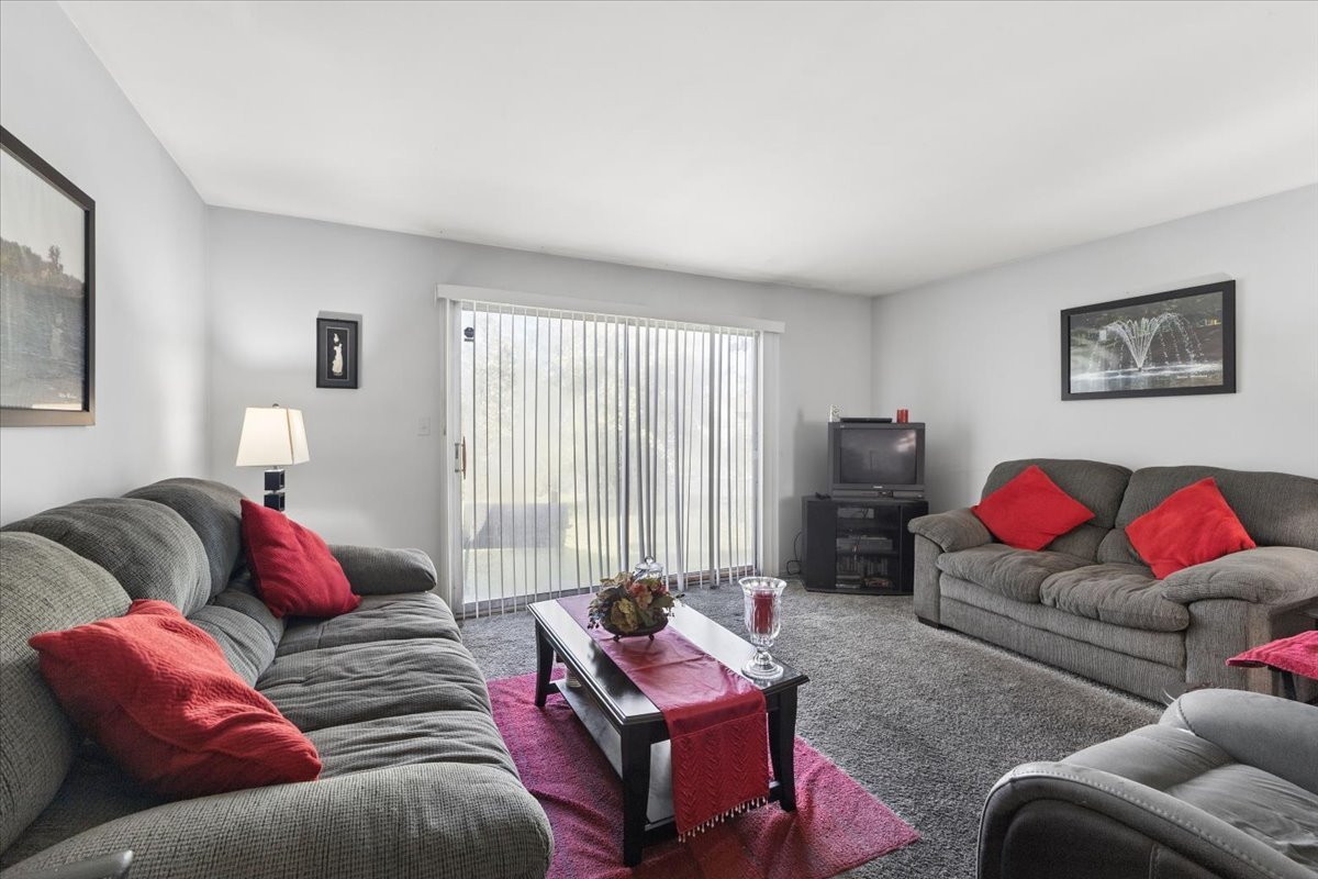 Living room with gray sofas, red pillows, and a sliding glass door.
