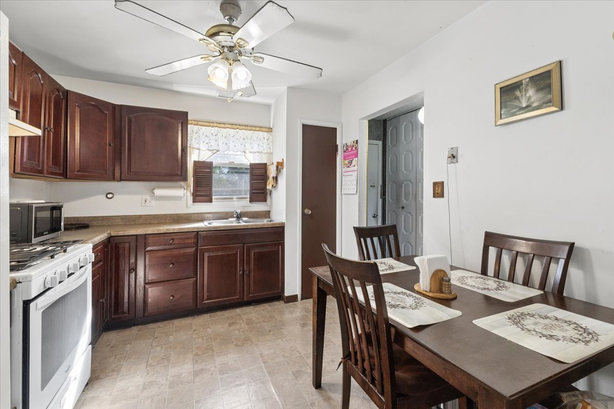 Kitchen and dining area with dark wood cabinets, a white gas range, and a dining table.